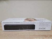 Box showing the AccuVoice AV157 TV Speaker with hearing aid technology, features and model name on packaging.