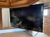 32 inch Insignia LCD TV mounted under kitchen cabinet, black bezel, model and labels visible.