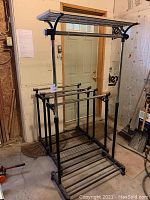 Large and two smaller clothing racks in a storage room with minor wear.