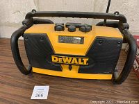 Front view of the yellow and black DeWalt battery charger and radio unit showing handle and speaker grills with DeWalt logo.