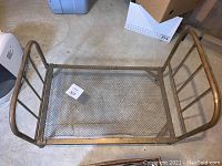 Full top view of the metal doll bed showing mesh metal base and rounded tubular bars of frame.