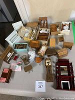 Full view of assortment of vintage doll furniture on tabletop, including multiple chairs, beds, small tables, drawer units, and various wooden pieces.