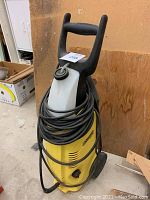 Front diagonal view of the yellow and black Karcher K3-79 garden sprayer showing coiled hose and handle.