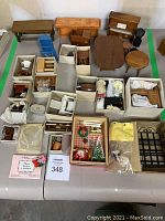 Top-down overview of lot showing multiple wooden doll furniture pieces and boxes containing miniature accessories.