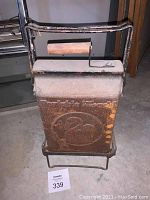 Front view of the hibachi showing wooden handle, 'Portable Hibachi' embossed text, and swan logo on metal body, mounted on wire stand.