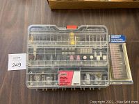 Clear plastic case with 300 Jobmate rotary tool accessory pieces visibly arranged inside, various sanding drums, polishing wheels, buffing pads, wire brushes and drill bits.