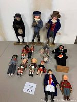 Full lot of 13 assorted Scottish, Irish, and British dolls arranged on a flat surface, showing variety of sizes and costumes