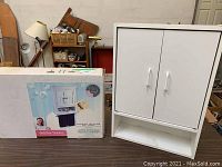 Two wall cabinets on table, one unopened and one opened showing minor wear