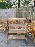 Front view of the 5 tier folding shelf showing all wooden planks and metal frame, with weathered wood and repair on the fourth shelf.
