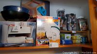 Shelved kitchen items including Presto Chip Shot potato chipper box, paper towel holder, and various storage containers.