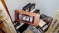 Wide view of large collection of photo frames, albums, and boxes in multiple stacks and boxes