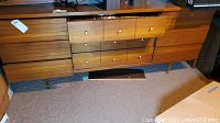 Full frontal view of dresser showing the nine drawers, wood grain finish, metal knobs and two drawers partly open.