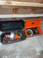 Two sets of power drain cleaners inside open carrying cases, showing the motor units, cords, and flexible hoses.