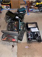 Photo of assorted power tools, hand tools, and toolboxes on a floor showing the variety in the lot