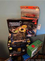 Photo showing a variety of unopened radio controlled vehicles, a Stock Car Raceway set, and boxed toy cars including a Matchbox truck and Automoblox vehicle.