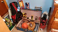Full view of sporting goods lot with golf bag, tennis rackets, dumbbells, basketball, vintage steamer trunk and various small fitness and sports items inside and around trunk