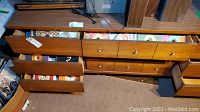 Mid-century modern wooden drawer unit with multiple open drawers filled with vinyl record sleeves