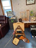 Two wooden wine racks, a wooden book holder, a pyramid shelf, two clocks, wooden decorative piece, flags and tray tables displayed together on floor and table.
