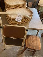 Photo showing stacked 24 bamboo trays on tabletop, folding card table and small wooden stool next to it