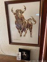 Framed John Fulton bull painting showing full bull image and signature with sculpture below.