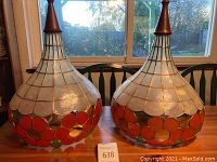 Pair of pear-shaped capiz shell lampshades with red-orange flower motifs, wood finials at top