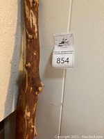 Close-up of the carved wooden walking stick showing natural wood texture and knots.
