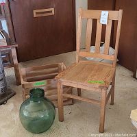 Image showing green glass jar, wooden slat crate, and oak chair placed on floor in a room.