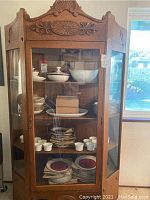 Front view of oak hutch with glass door and visible interior shelves