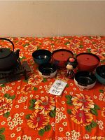 Overview of Japanese snack bowls, tea kettle, and doll on floral tablecloth