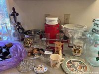 Wide view showing variety of glass milk bottles, kitchen bowls, vintage cups, and collectible plates