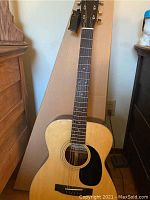 Full view of Montoya acoustic guitar showing natural wood finish, six steel strings, black pickguard, and wooden bridge.