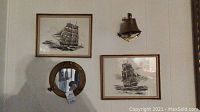 Two framed ship pictures by Robert James Pailthorpe mounted on wall with mirrored brass porthole and brass bell above them