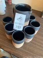 Photo showing all 6 matching pottery cups arranged around the pitcher on a table, highlighting the color scheme and matching design of the set.