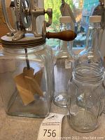 Photo showing the vintage butter churn with crank handle and wooden paddles inside, along with bottles and jars in front