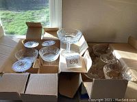 Two open cardboard boxes containing six Waterford Lismore champagne glasses each