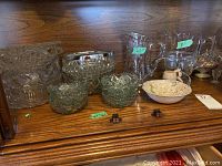 Photo of various clear carnival and patterned glass bowls, advertising sizes (8.5 inch pitchers, 13 inch compote).