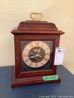 Full view of Bulova wooden mantel clock with brass top handle and glass front, showing size label 10.5x7.5x15 inches.