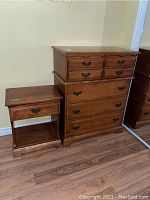 View of matching wood highboy dresser and nightstand showing four-drawer dresser and single-drawer nightstand with open shelf below