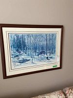 Framed print hung on a wall showing snowy forest and two deer.