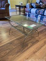 Front angled view of the rectangular glass top coffee table showing the metal curved rack base and legs.