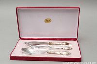 3-piece flatware set in original red box with pink satin lining, sterling silver handles visible
