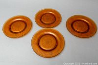 Top view showing four amber luncheon plates with raised cornflower design in the center and etched floral designs on rim