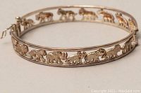 Close-up angle showing the pierced elephant pattern around the silver bangle bracelet and the hinge closure.