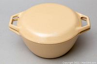 Closed Dutch oven in beige enamel, showing lid and handles.