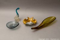 Four glass items arranged on gray surface showing size and shape: smoked glass planter, small bowl, Murano swan figurine, gold flecked ashtray