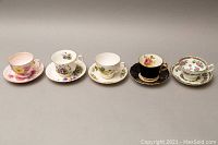 Five Royal Albert tea cups with matching saucers arranged side by side showing varied floral and ornate patterns