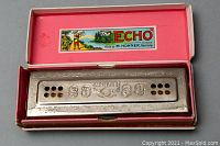 Harmonica in original pink and red box showing 'The ECHO' with M. HOHNER made in Germany marking.