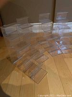 Four clear acrylic rising display stands arranged on the floor showing their stepped design