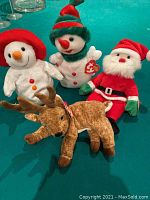 Front view of all four Ty Beanie Babies Christmas characters including Santa, two snowmen, and reindeer all with tags.
