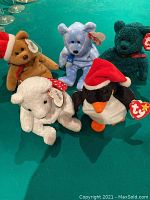 Five Ty Holiday Beanie Babies arranged on a green surface, showing all figures with tags visible.